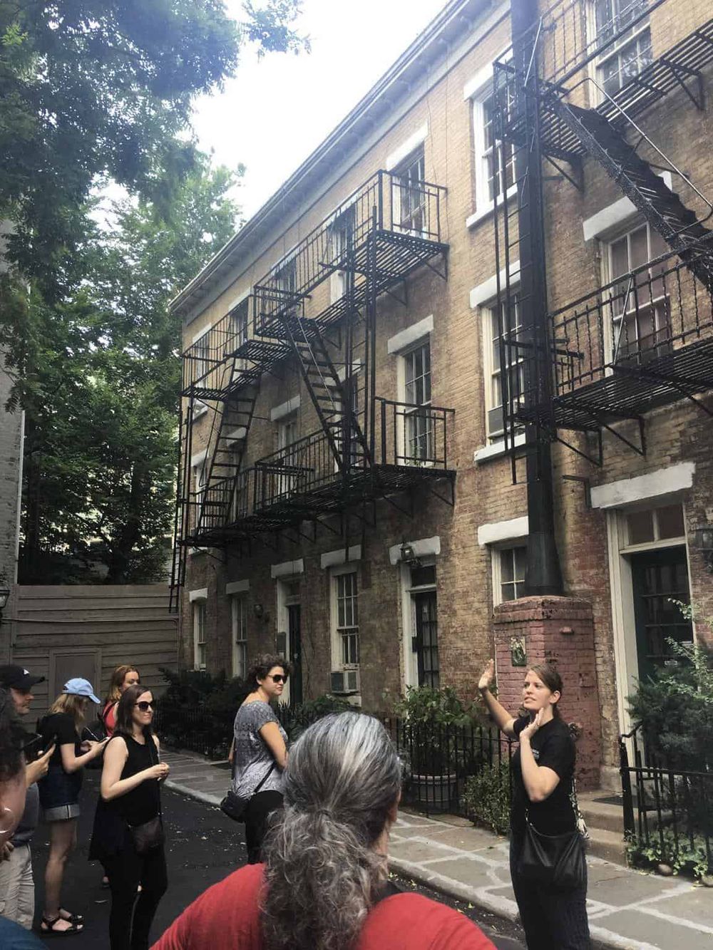 Historic building with fire escape in an urban neighborhood, guided tour with a guide explaining local history.