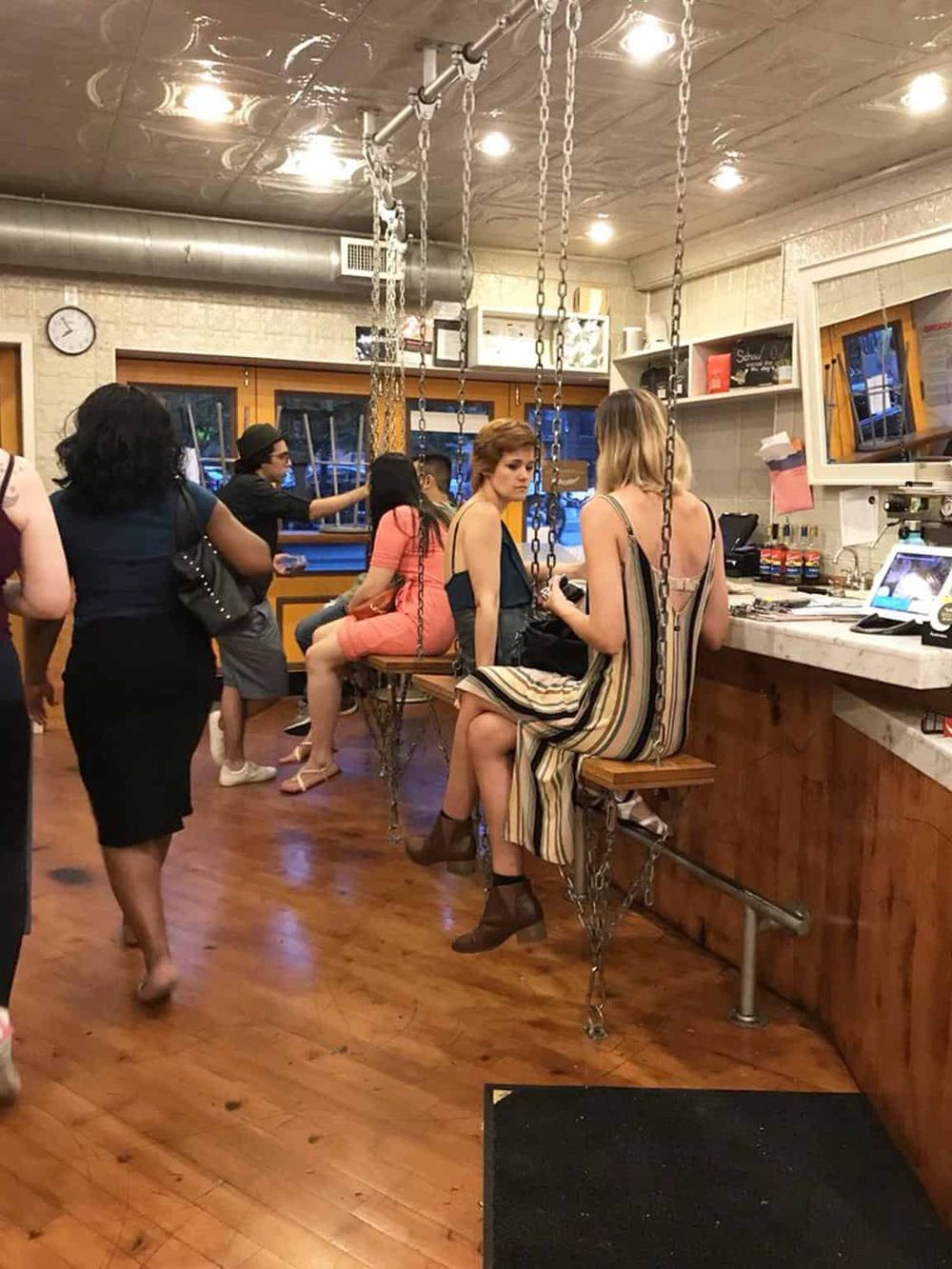 Charming bar interior with chain-suspended seating, lively atmosphere, and modern decor for socializing and dining.