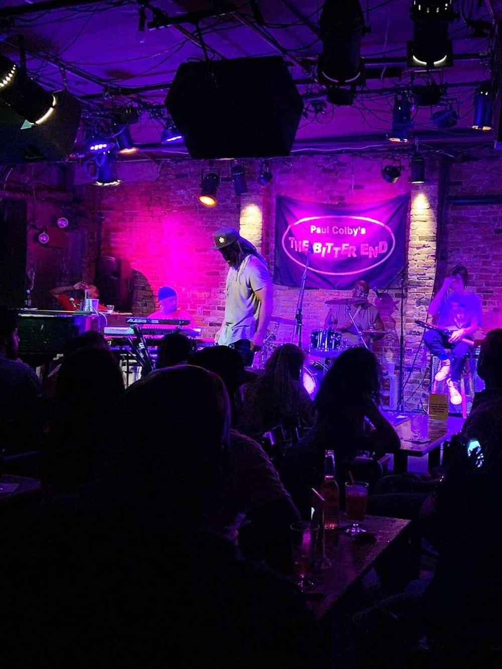 Live music performance at The Bitter End, NYC, vibrant purple lighting, intimate venue, popular nightspot.