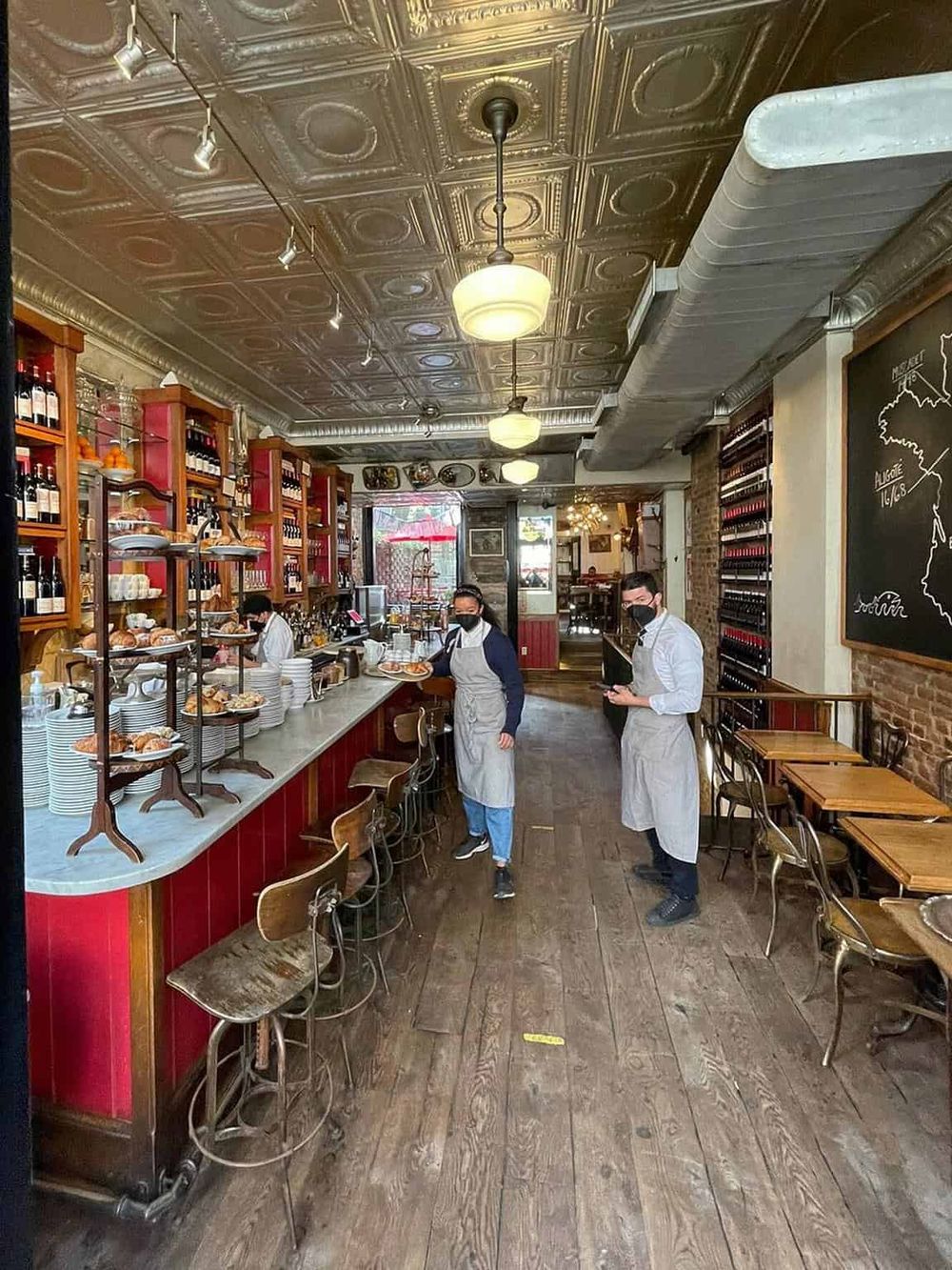 Cozy restaurant interior with vintage ceiling, staff in masks serving breakfast in a warm, inviting atmosphere.