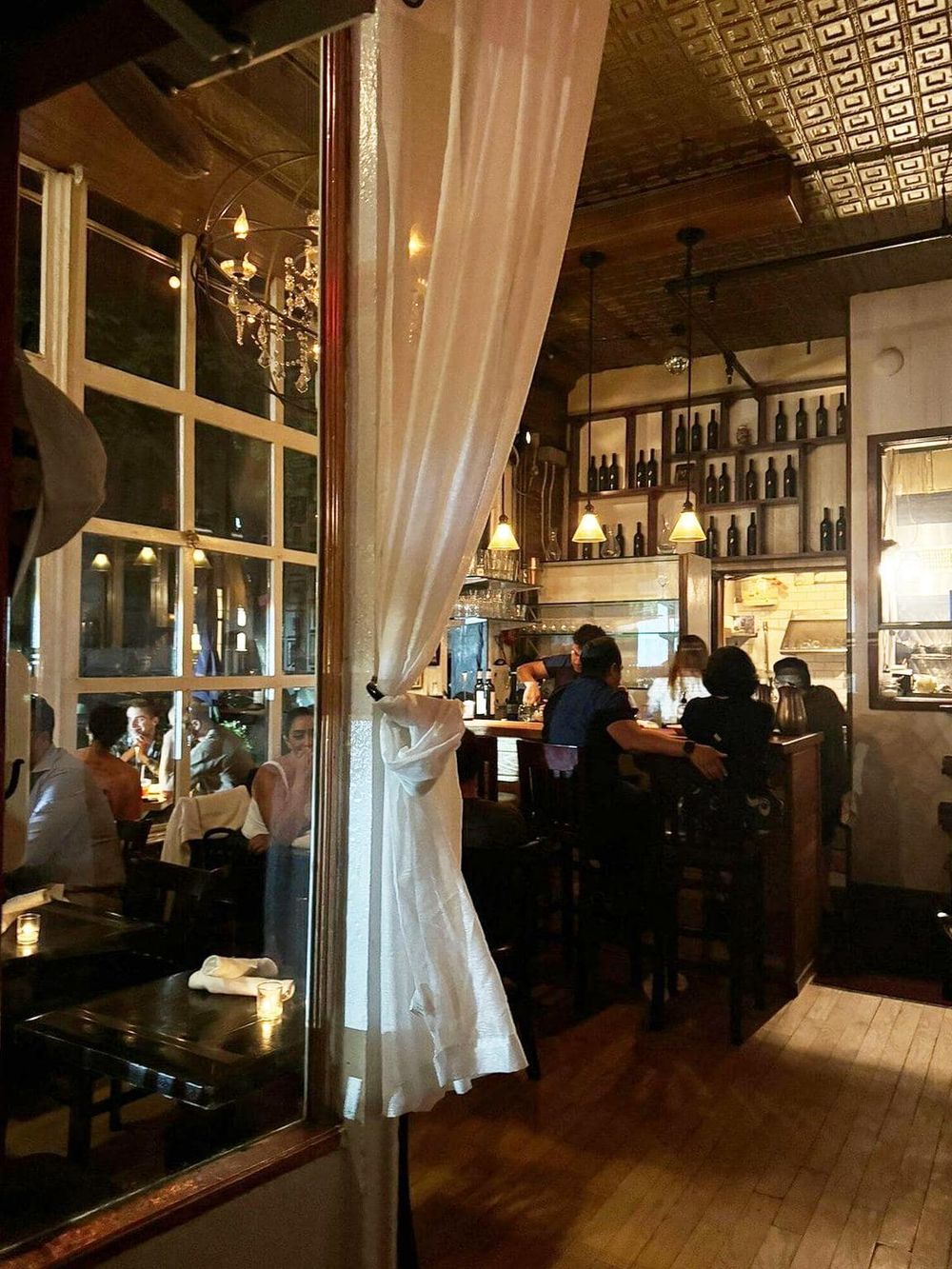 Cozy restaurant interior with warm lighting, wooden accents, and a lively atmosphere for dining and socializing.