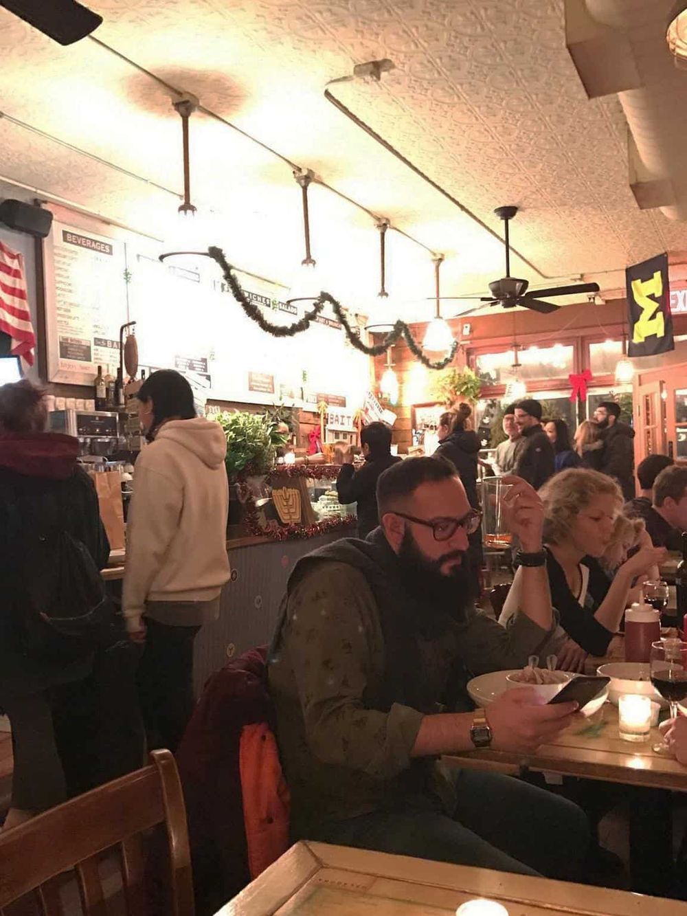 Cozy restaurant interior with diners enjoying meals, festive holiday decorations, and a lively atmosphere.