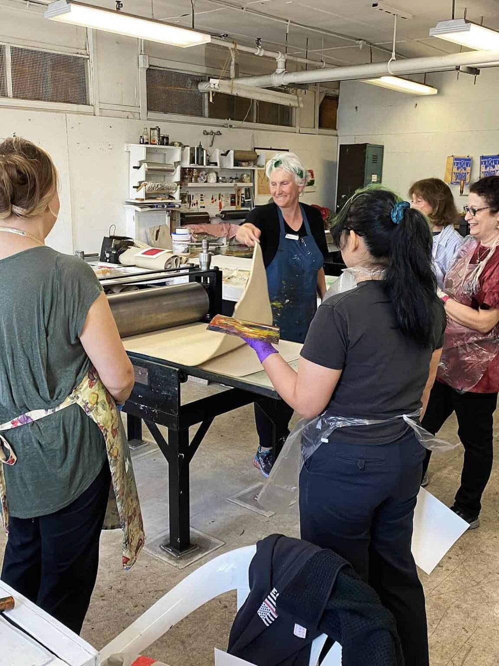 Colorful art class participants learning printmaking techniques at QuestForDirections studio.