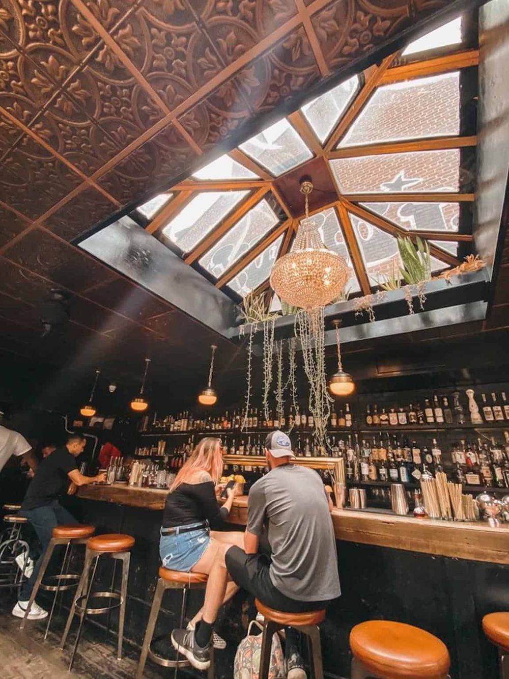 Vibrant bar interior with a glass ceiling and warm ambient lighting, perfect for social gatherings.