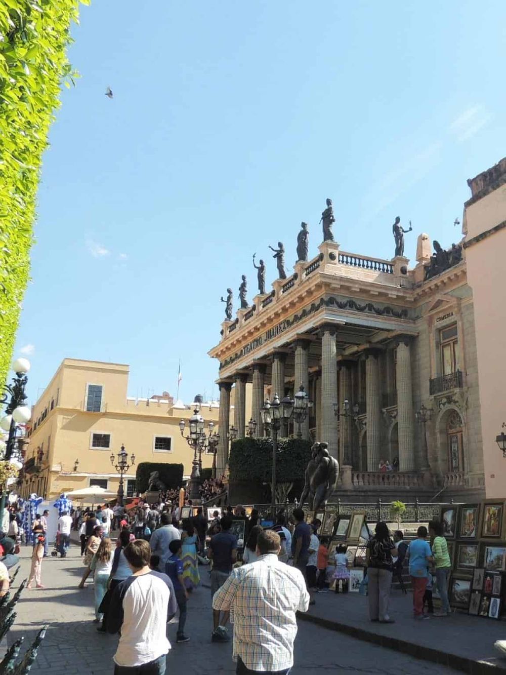 Historic theater building with statues and street art market, outdoor cultural scene, popular tourist destination in Mexico City.