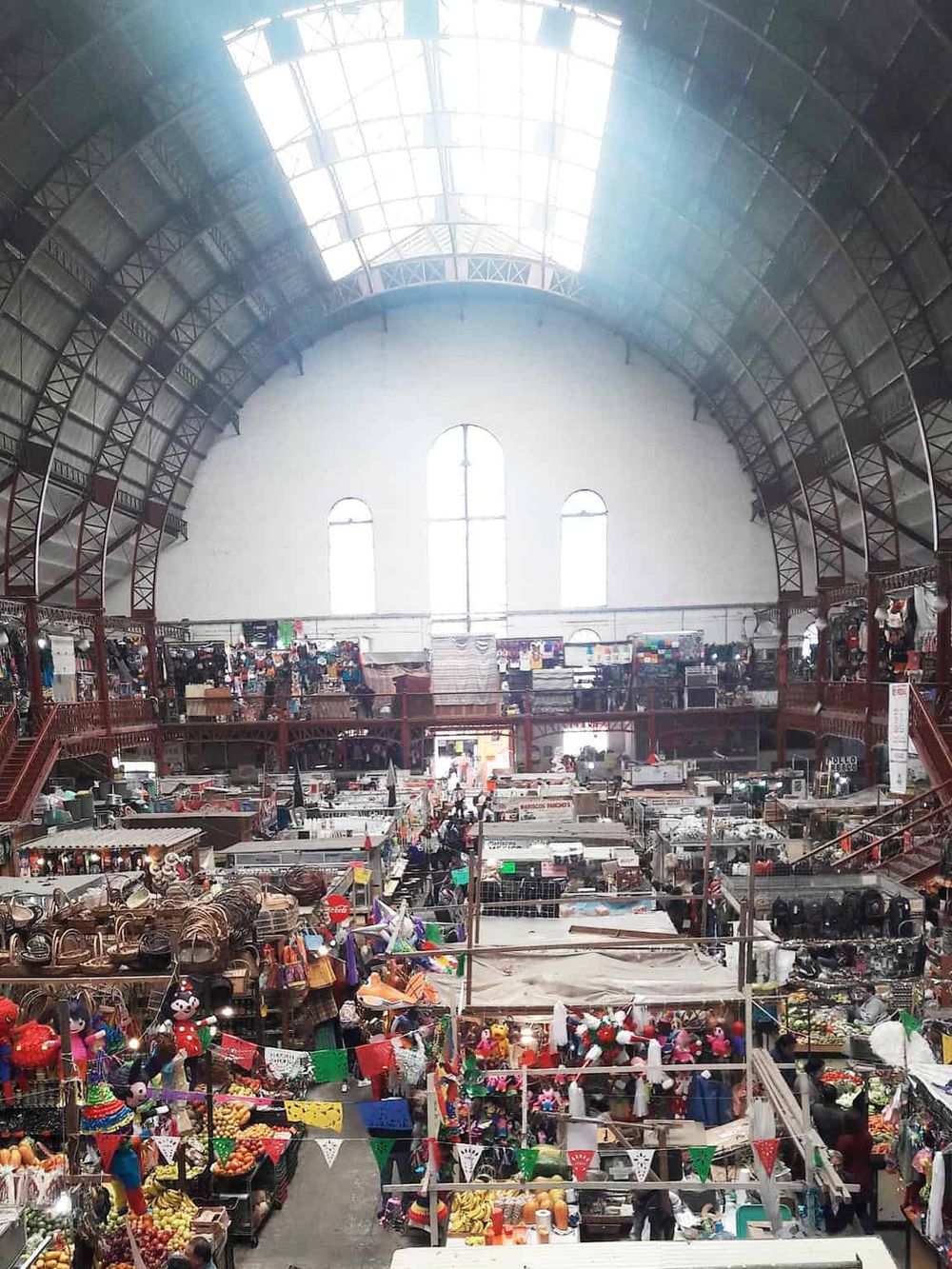 Colorful indoor market with vendor stalls and high arched ceiling, perfect for shopping and exploring local goods.