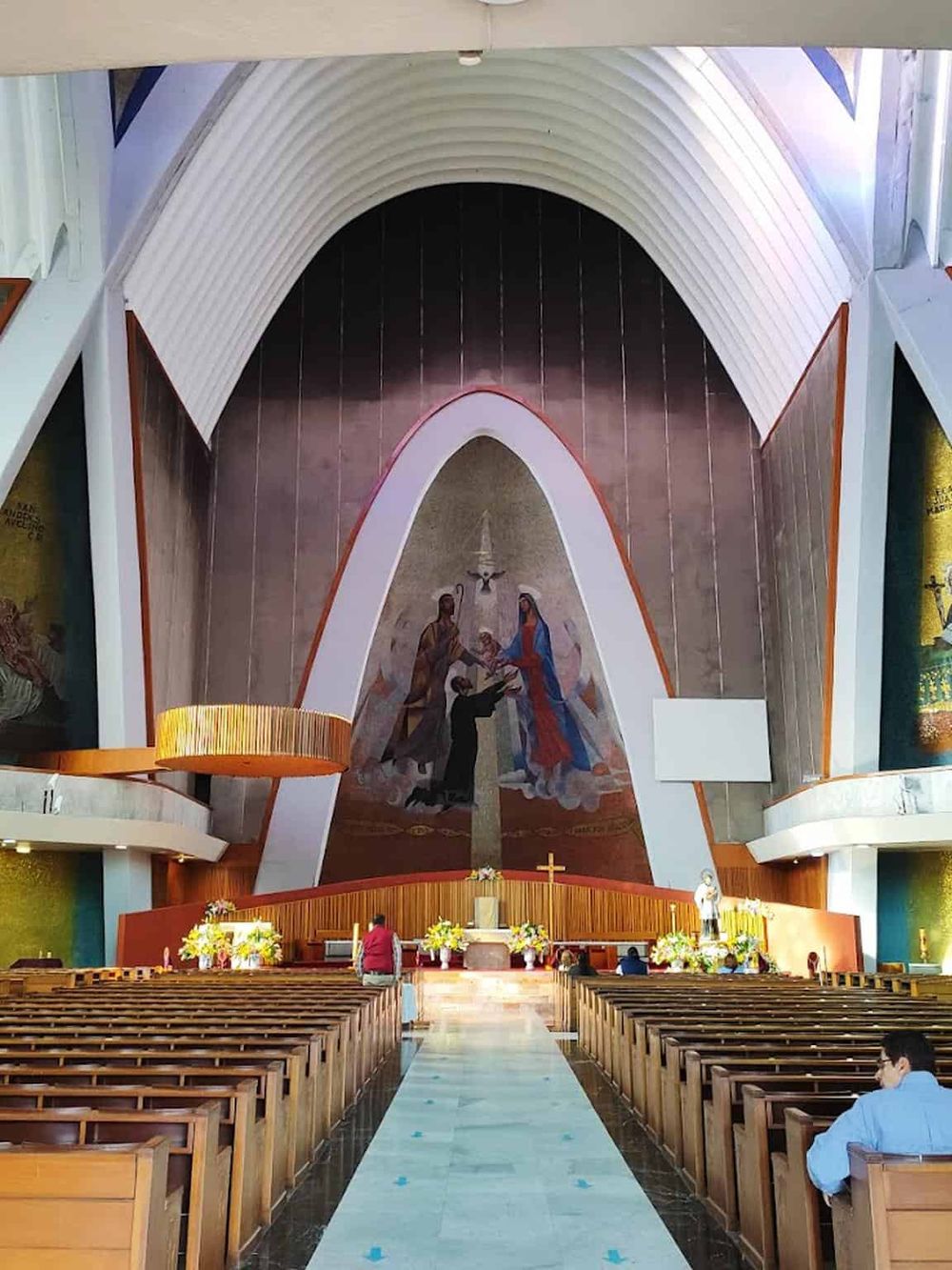 Serene church interior with catholic altar, vibrant mural, and wooden pews for worship. Perfect for spiritual journey and community gathering.