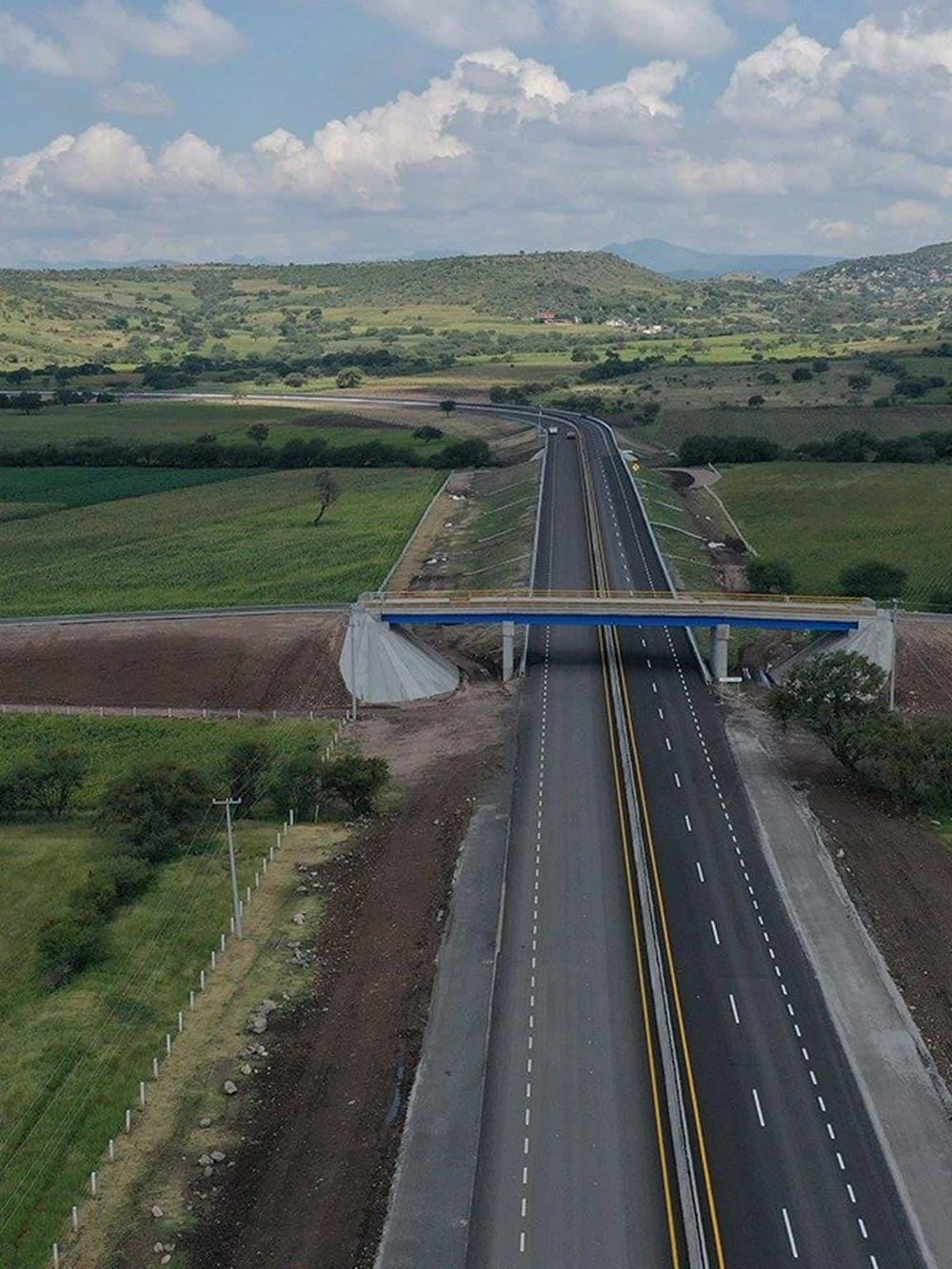 Scenic highway with bridge in rural landscape, ideal for travel guidance and navigation.