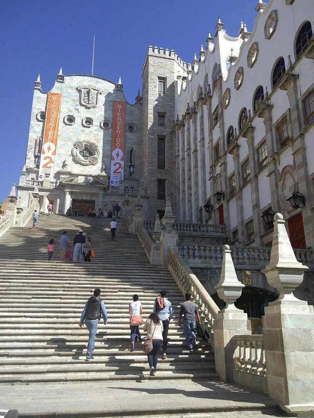 Renaissance-style castle with wide staircase and tourists, architecture inspired by historic European castles.