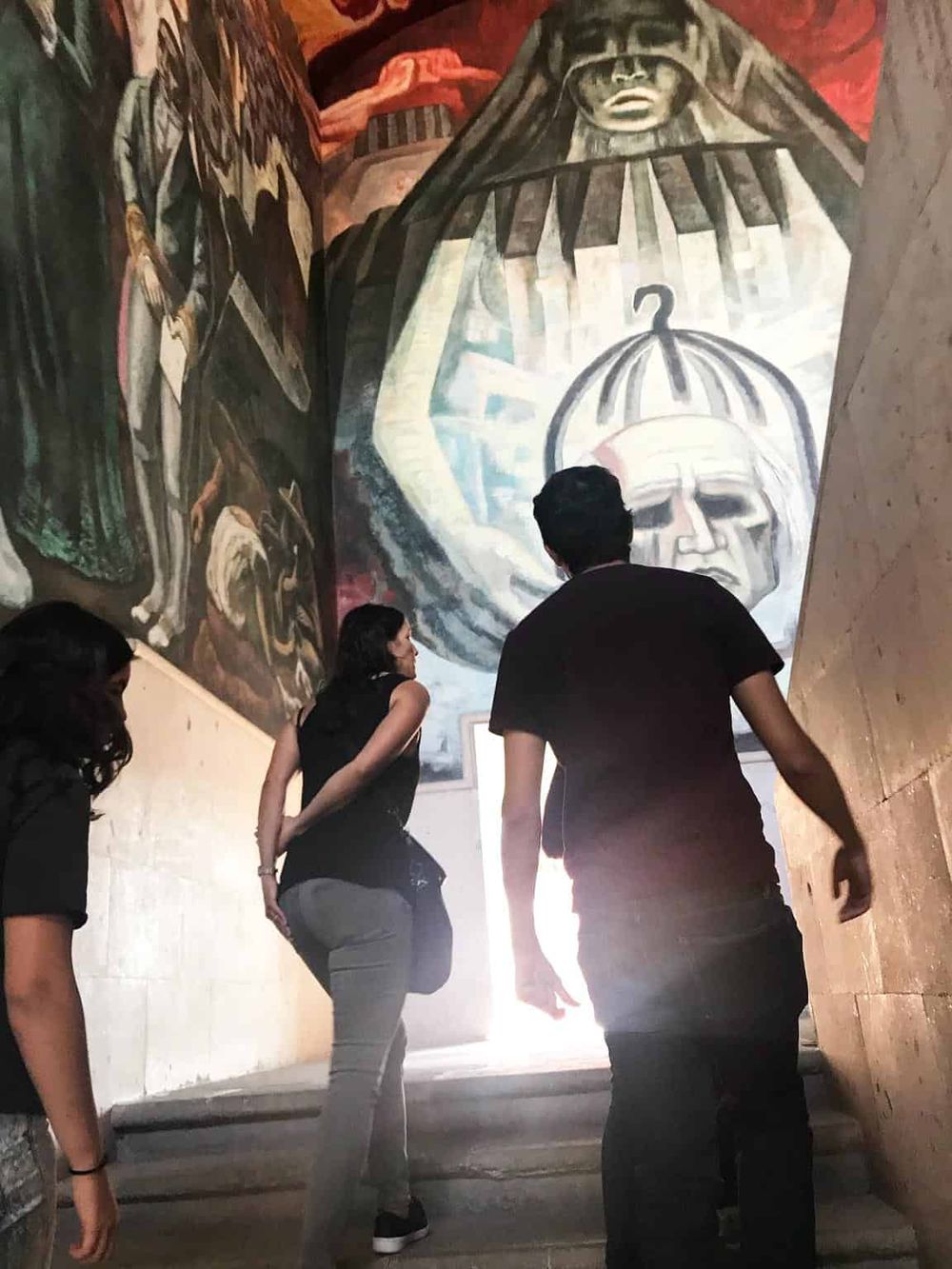 Vibrant mural art featuring a large statue and people exploring cultural history and heritage.