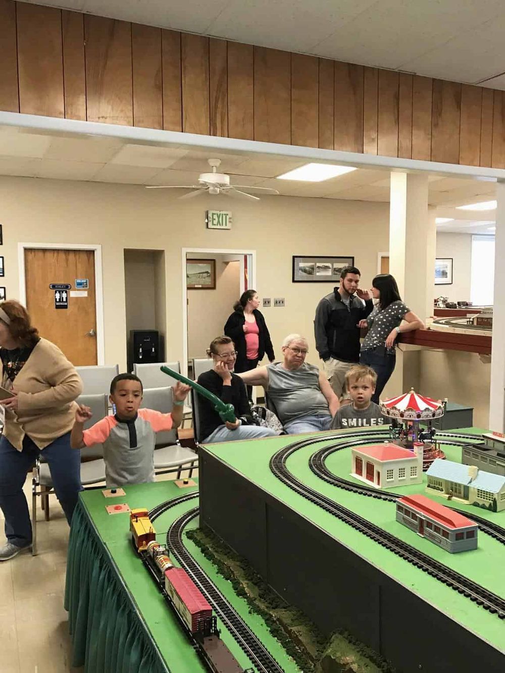 Model train display at Quest For Directions community event, family enjoying train set and kids playing.