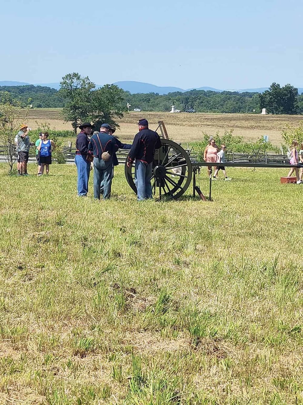 Historic Civil War reenactors demonstrating a cannon at an outdoor event in a grassy field.