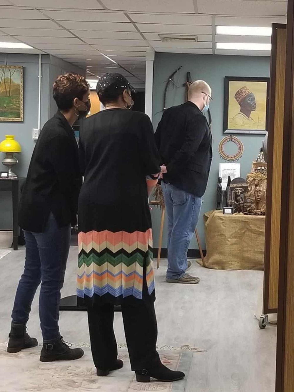 Diverse group viewing African tribal art at QuestForDirections cultural center, showcasing authentic African craftsmanship.