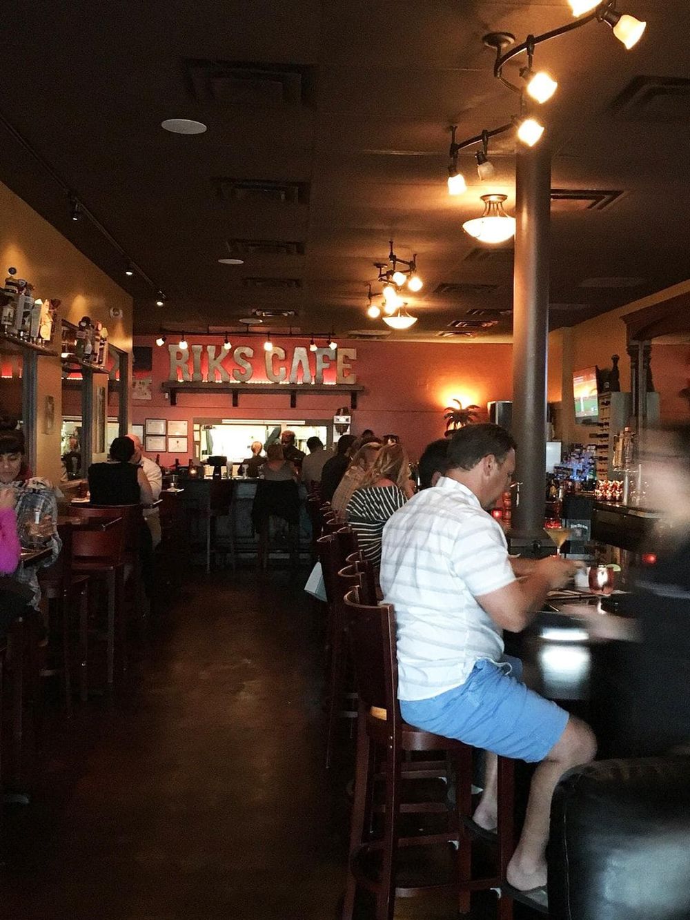 Cozy bar interior at Riks Café with customers enjoying drinks, dim lighting, and a casual atmosphere for social gatherings.