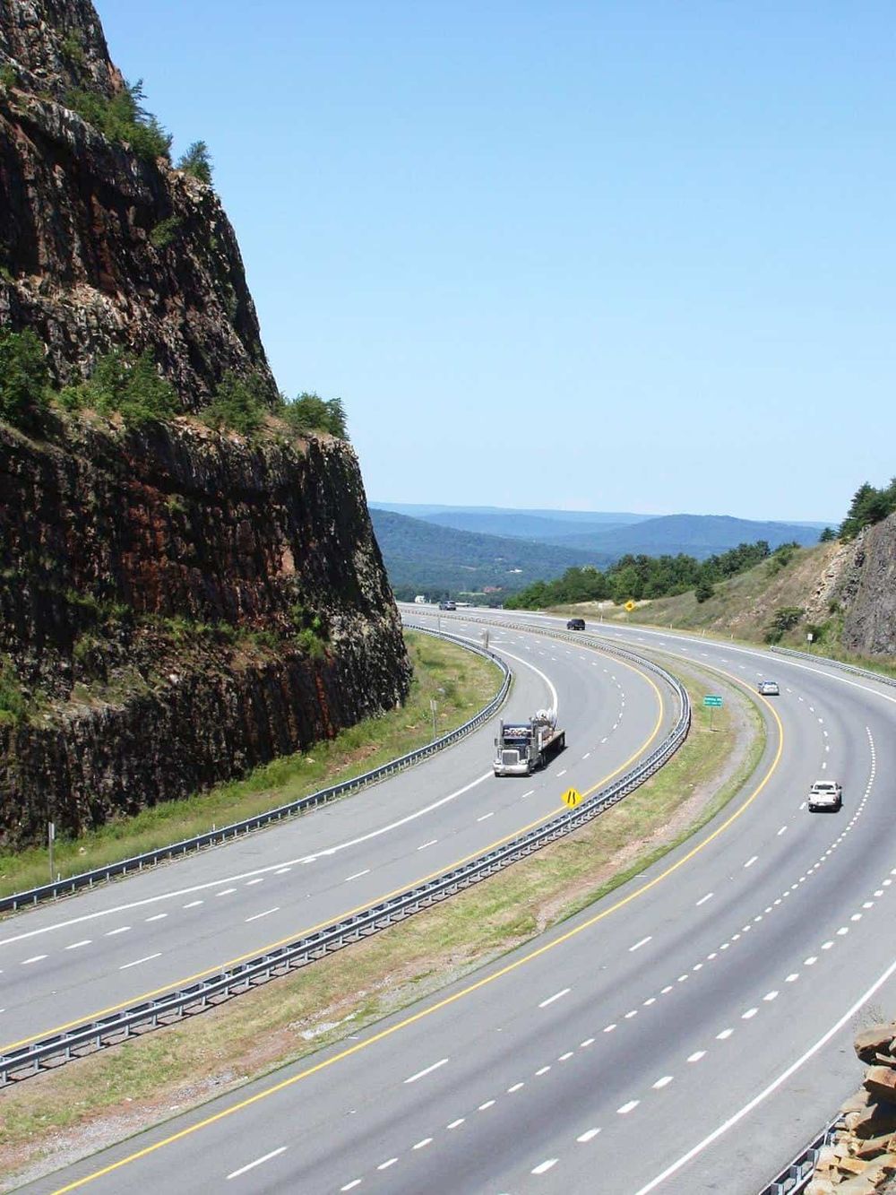 Scenic highway with mountains and vehicles, showcasing navigation and travel routes.