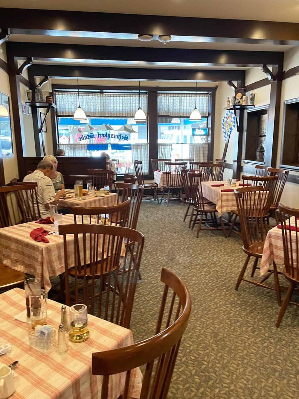 Comfortable Bavarian-style restaurant interior with wooden chairs, checkered tablecloths, and a cozy ambiance.