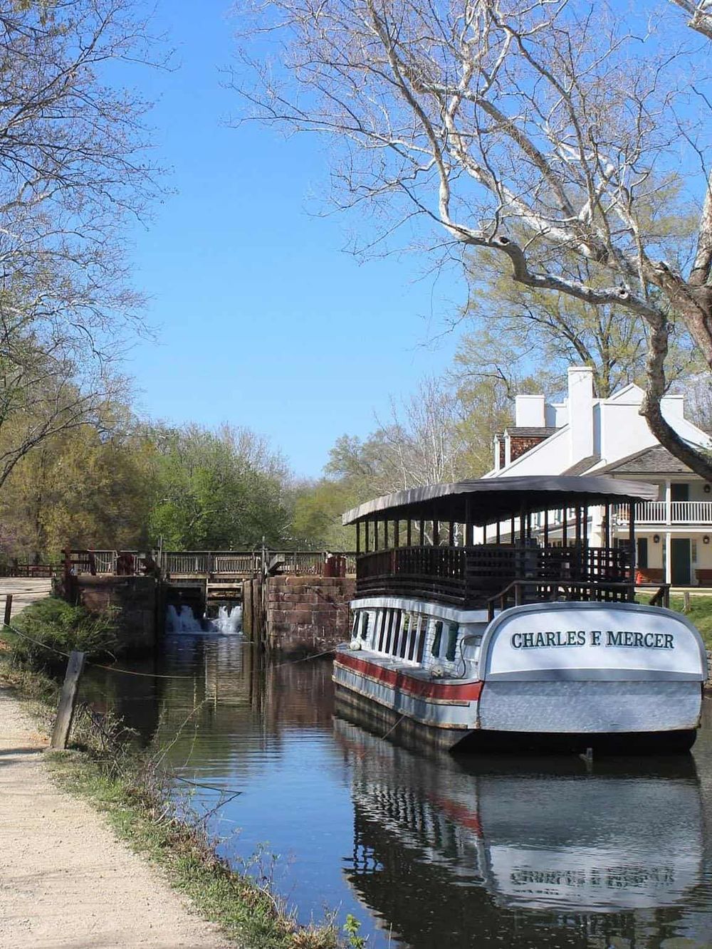 Vintage canal boat on a serene waterway in a park setting.