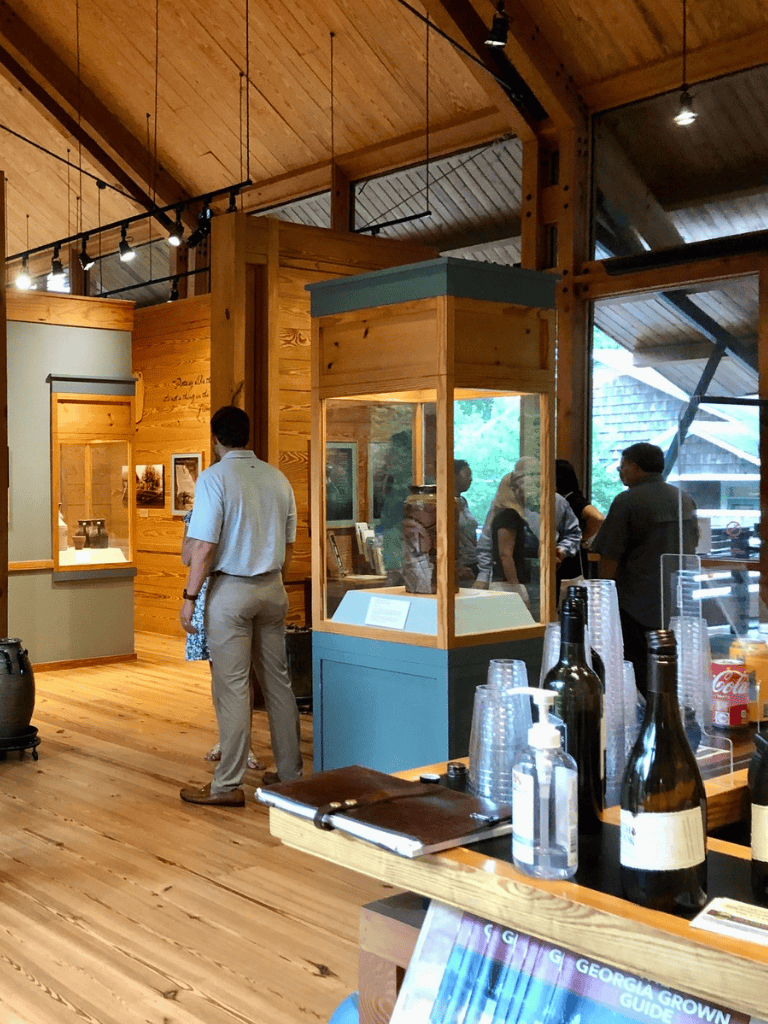 Museum exhibit with wooden interior, display cases, and visitors exploring artifacts inside QuestForDirections.