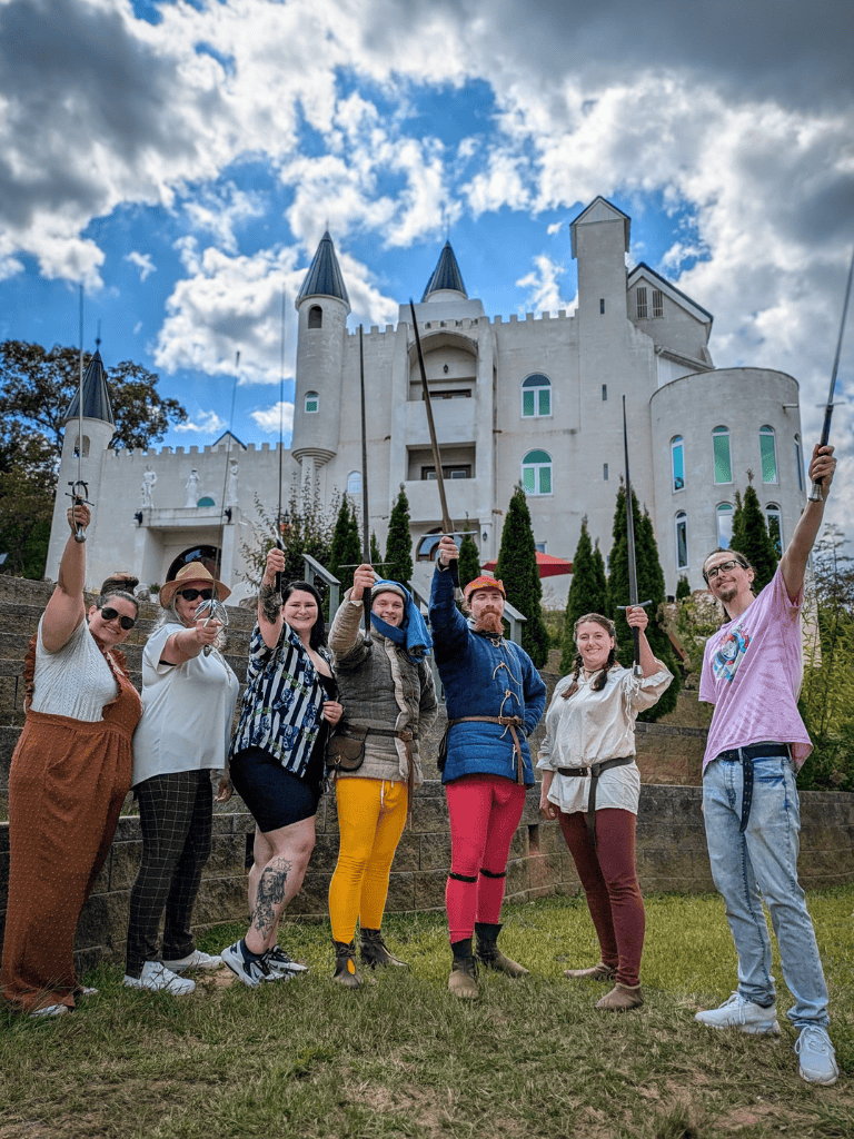 Medieval castle tour with smiling diverse group of tourists and flags, QuestForDirections travel experience.