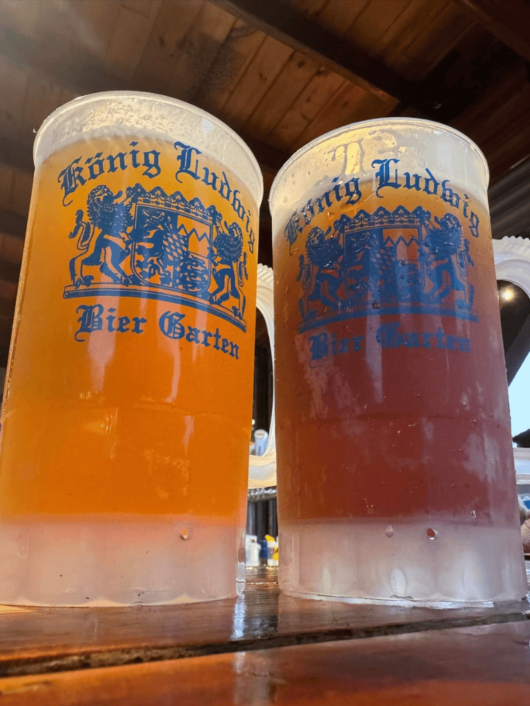 Cold beers in large glass mugs at König Ludwig Biergarten, celebrating Bavarian beer culture.