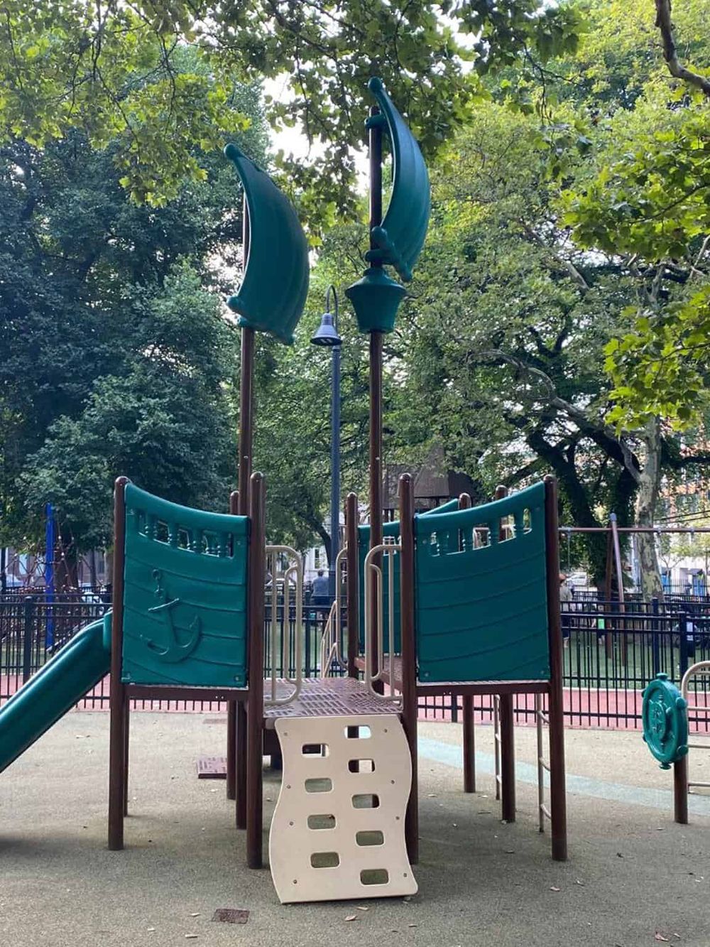 Colorful playground play structure with slides and climbing elements in a park setting.