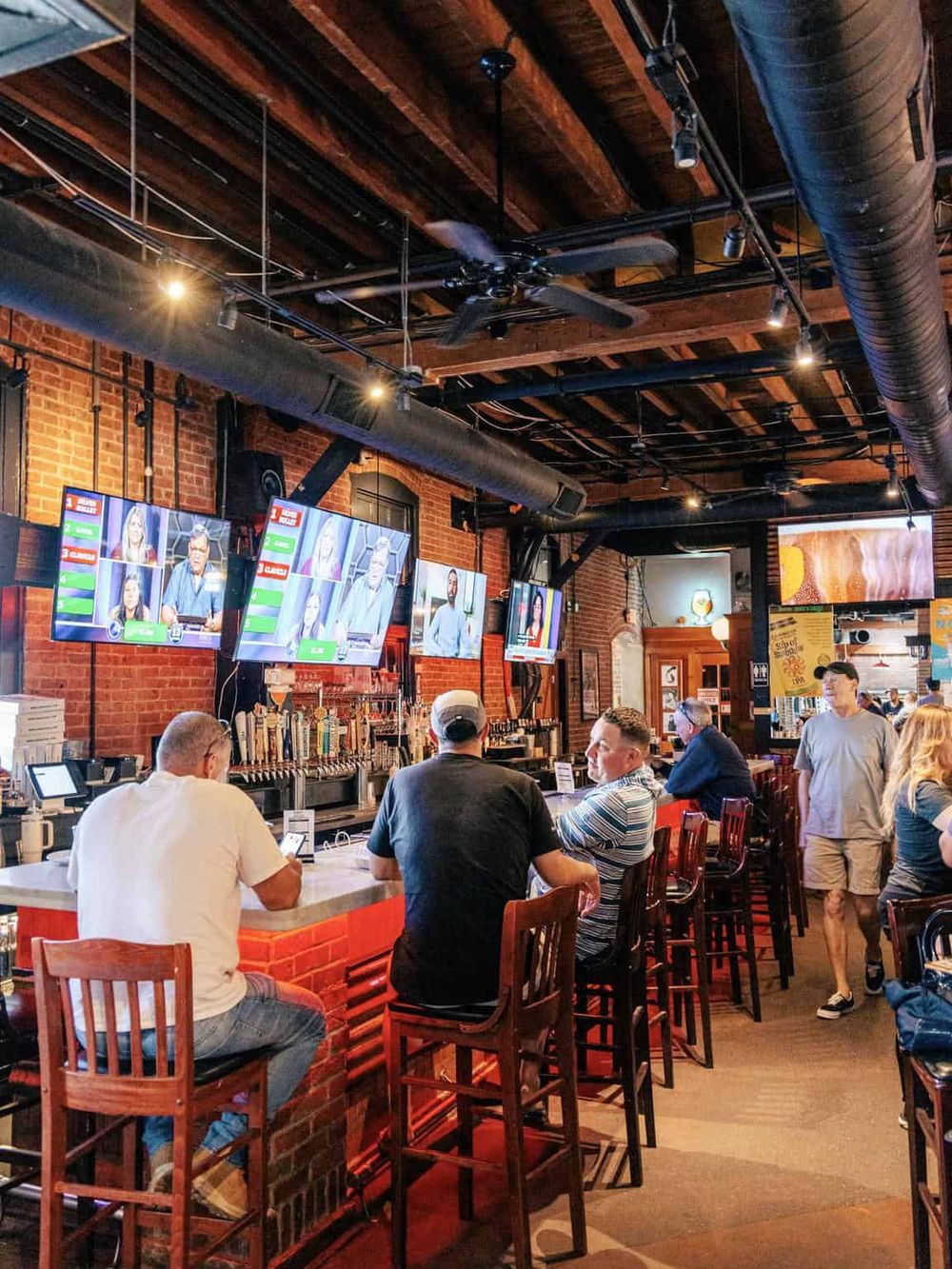 Vibrant sports bar interior with multiple screens, patrons watching live games, and a lively social atmosphere.