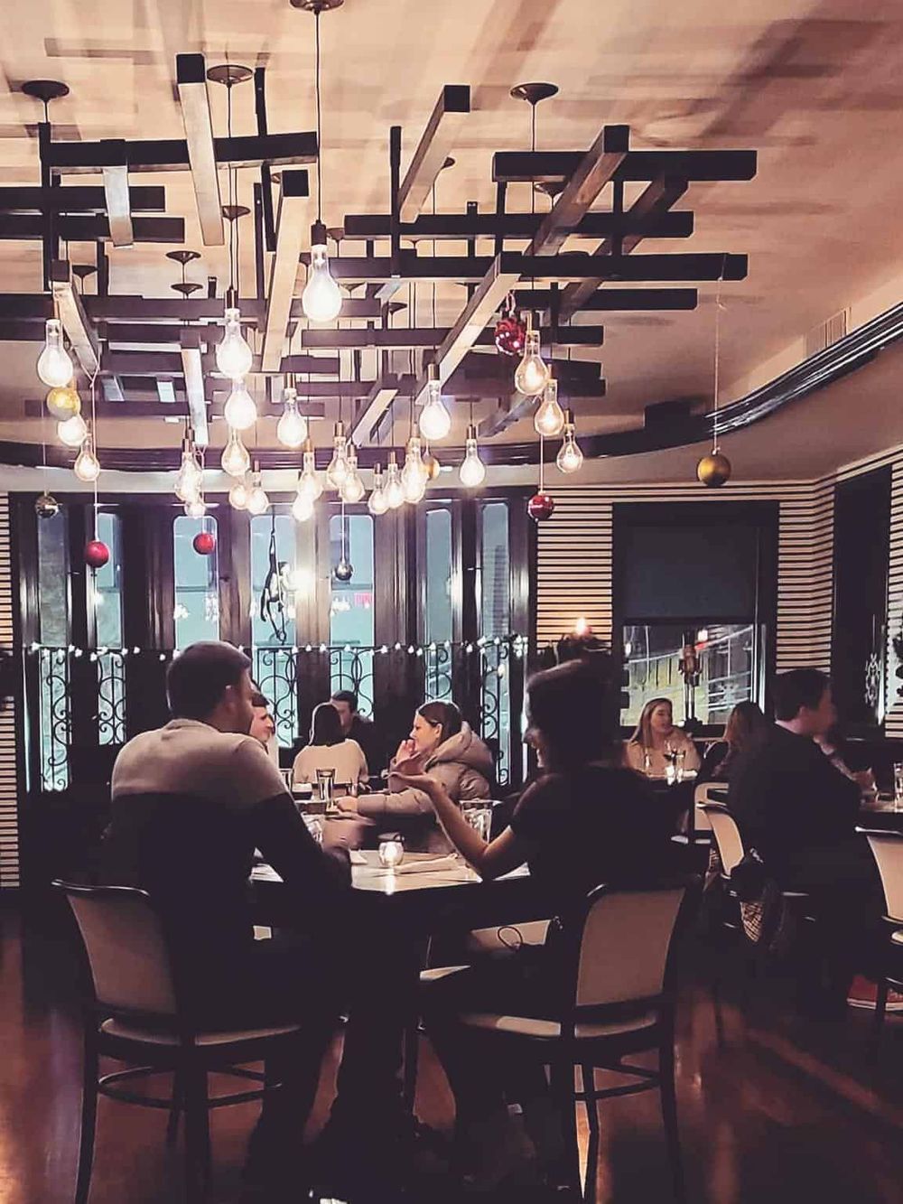 Modern restaurant interior with stylish lighting and group of people dining.