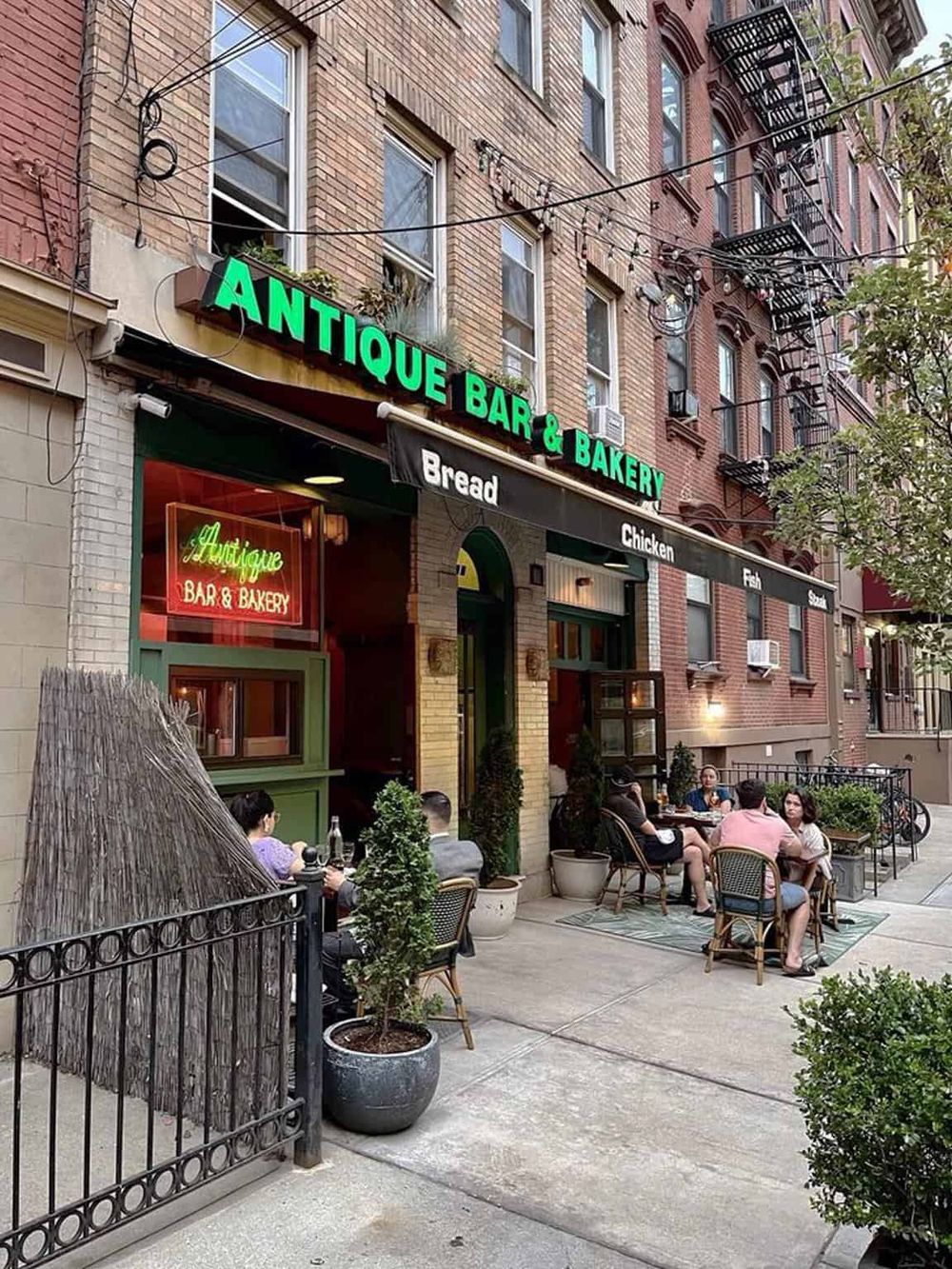 Vintage antique bar and bakery in city neighborhood with outdoor seating, adding charm and community appeal.