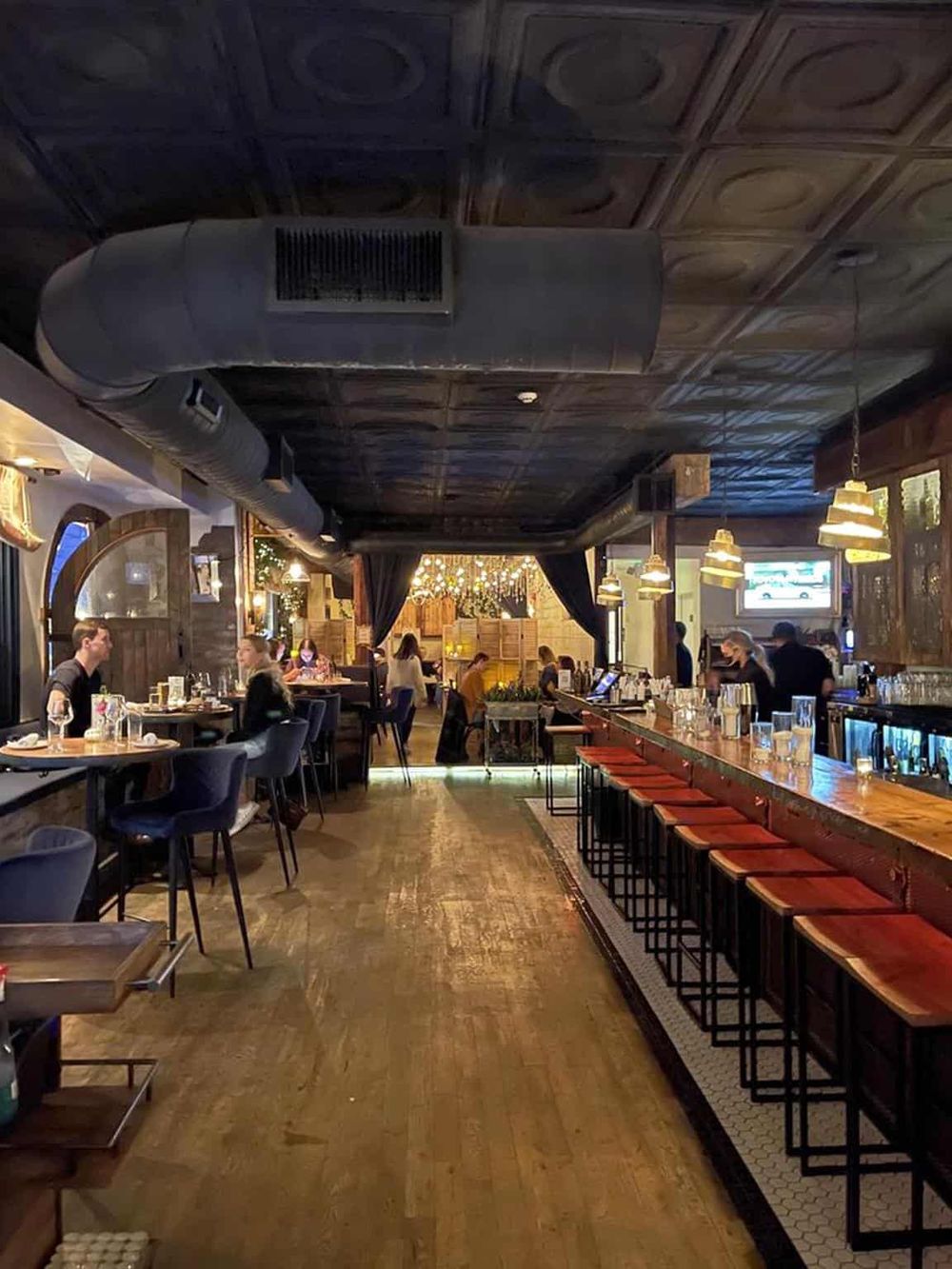 Cozy restaurant interior with wooden accents, bar seating, and warm lighting for dining experiences.