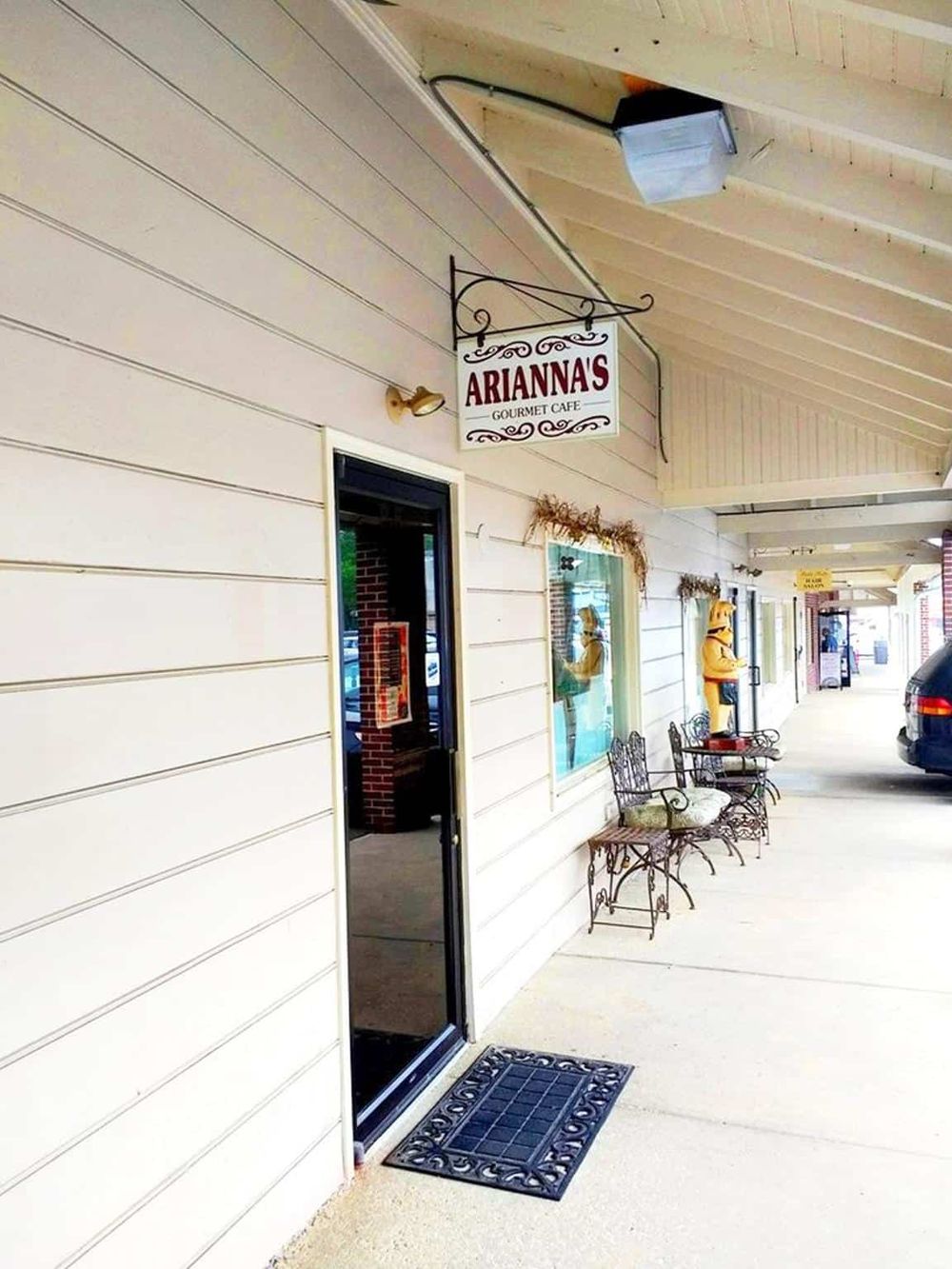 Cozy gourmet café storefront with outdoor seating and charming decor.
