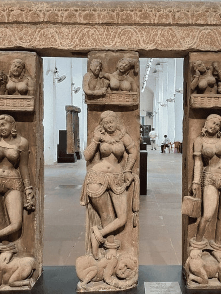 Elegant ancient stone carvings of female figures with intricate jewelry and patterns, displayed in a museum setting.