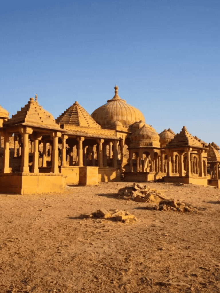 Ancient Indian temple ruins in desert landscape with clear blue sky, showcasing historical architecture and cultural heritage.