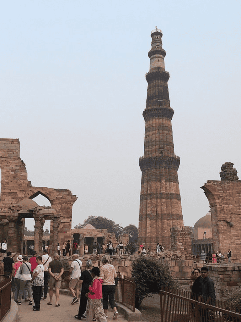 Ancient Qutub Minar, a UNESCO World Heritage Site in Delhi, India, surrounded by visitors and historical ruins.
