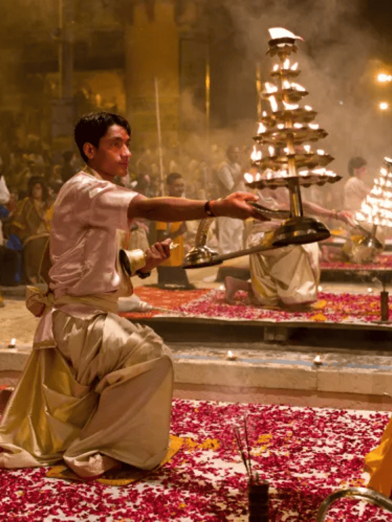 Bright Hindu priest performing traditional ritual with lamps during temple ceremony.