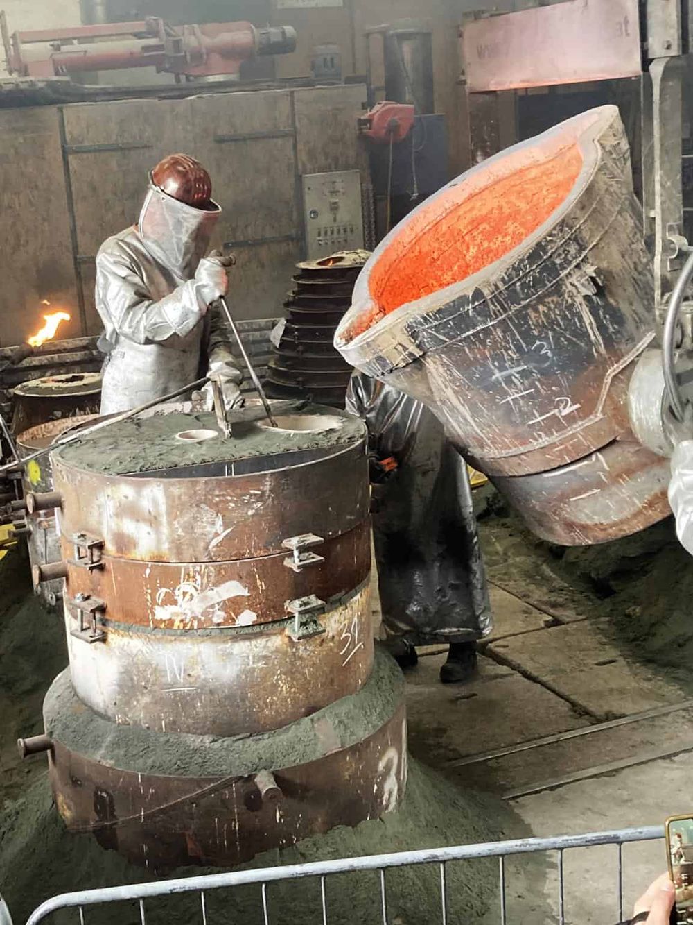 Molten metal pouring in foundry for manufacturing, industrial metal casting process.