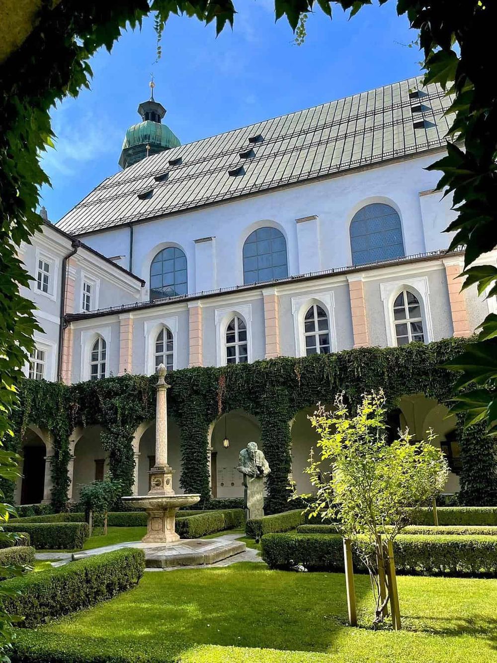 Ancient European church with courtyard, greenery, and fountain, perfect for historical travel and exploration.