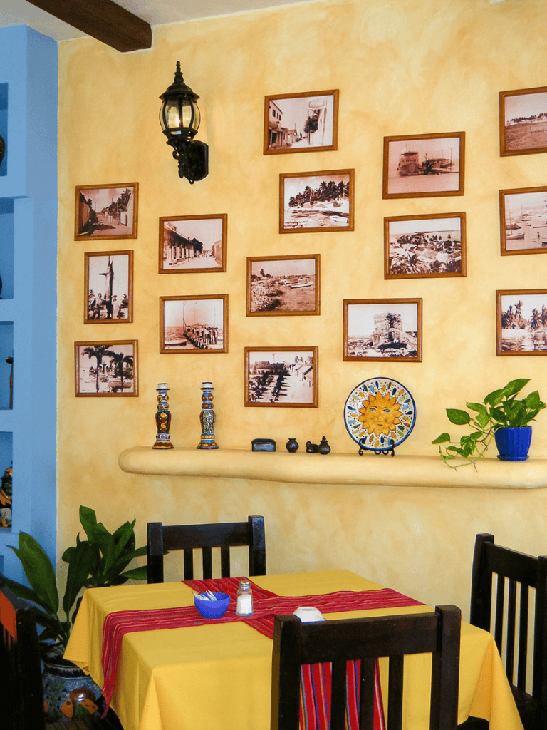 Colorful interior decor of a cozy restaurant with framed artworks and vibrant table setting.