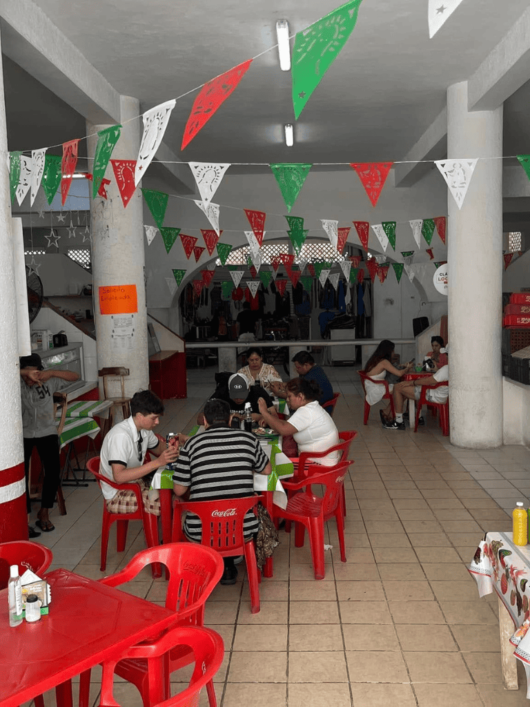 Colorful Mexican Independence Day celebration with festive banners, tables, and people dining.
