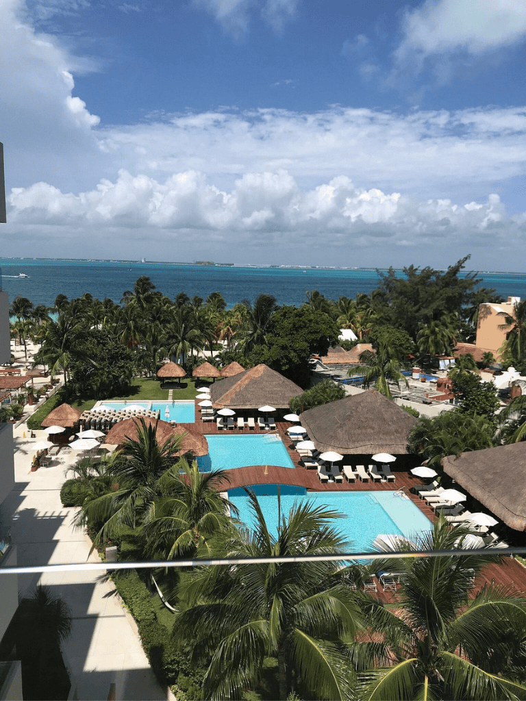 Relaxing resort pool with ocean view and lush tropical landscaping in Cancun, Mexico.