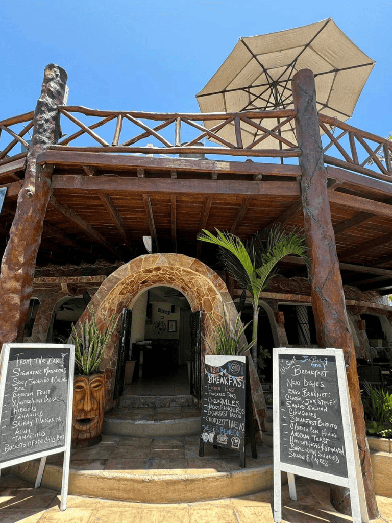 Relaxed tropical restaurant with outdoor balcony and sunshade umbrella, perfect for vacation dining.