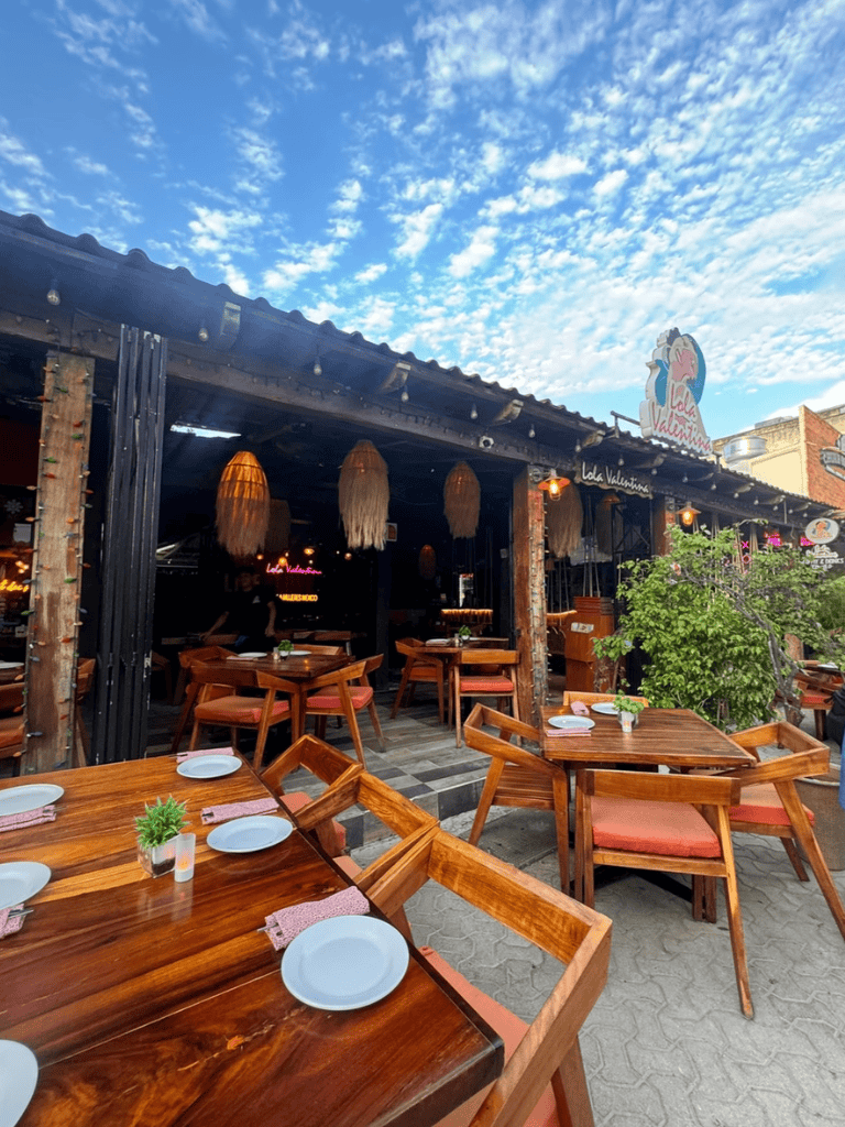 Cozy outdoor restaurant patio with wooden tables and chairs, vibrant sky, perfect for dining and relaxing, QuestForDirections.