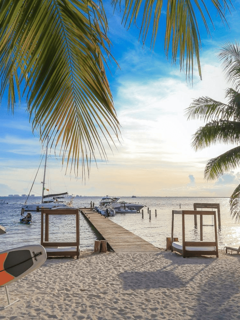 Relaxing tropical beach with sailboats and wooden pier, perfect for seaside adventures and vacation destinations.