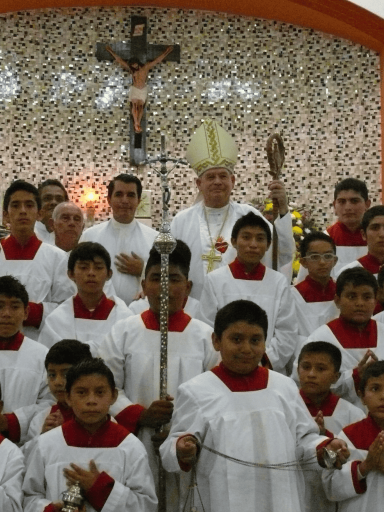 Children in choir robes with bishop and crucifix in church, religious ceremony, QuestForDirections.