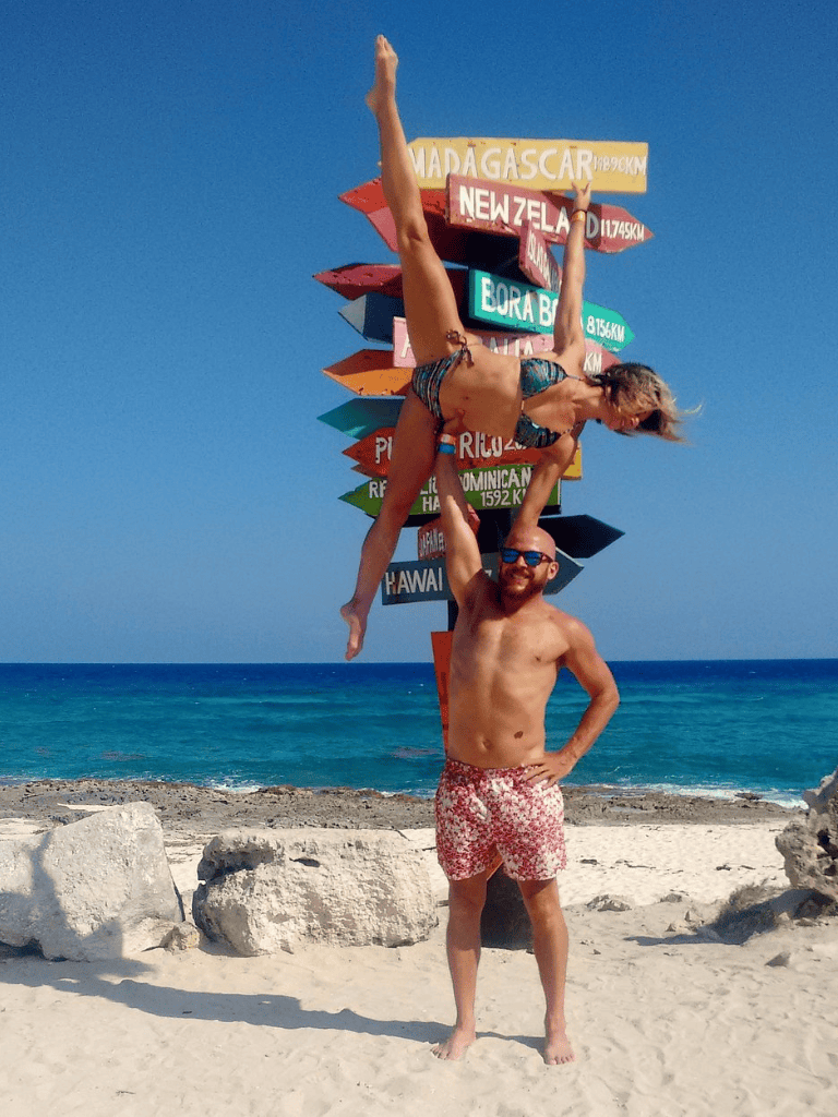 1. Bright beach scene with signpost, man, woman, and ocean backdrop.