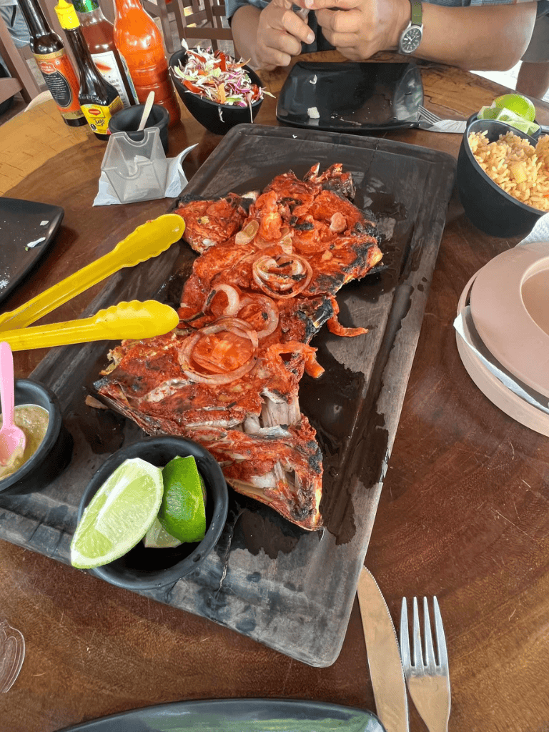 Grilled fish with lime and salad; Mexican seafood dish served with condiments and beverages.