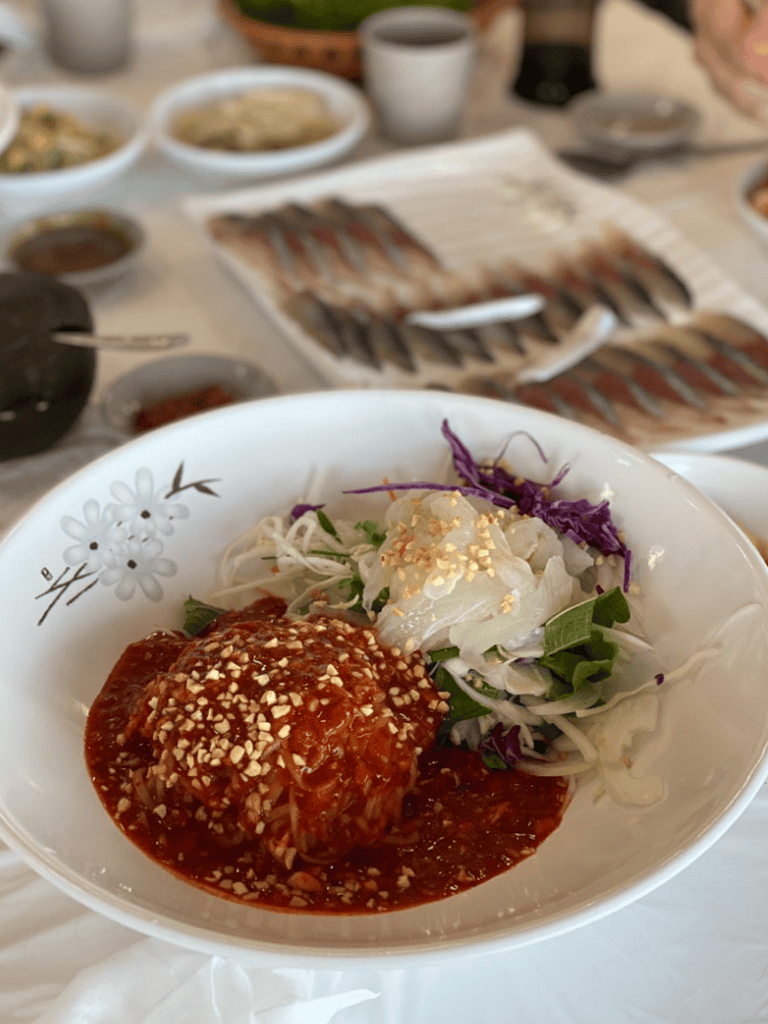 Warm Asian meatball with vegetable salad, crispy toppings, on white plate in a cozy dining setting.