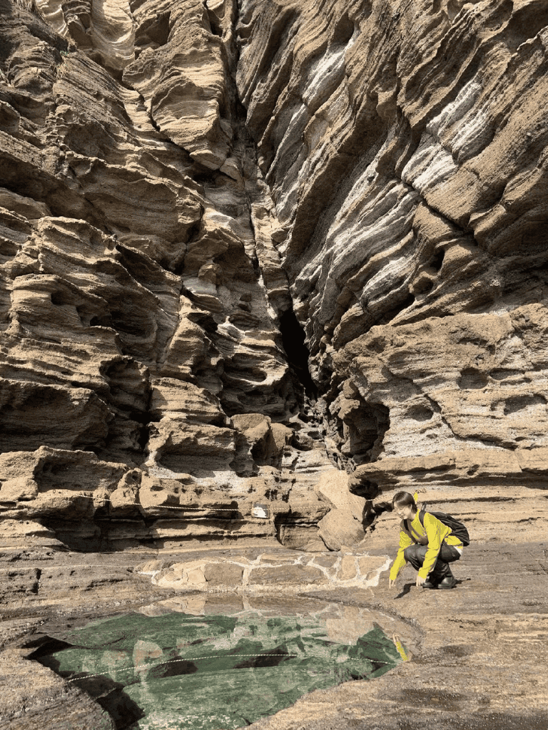Unearthing geological formations in the canyon, showcasing natural rock layers and a person examining a rock pool.