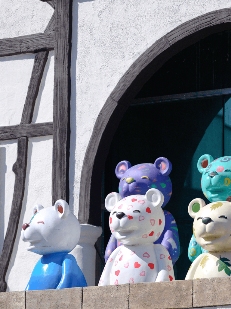 Colorful bear sculptures on building facade, whimsical outdoor art display.