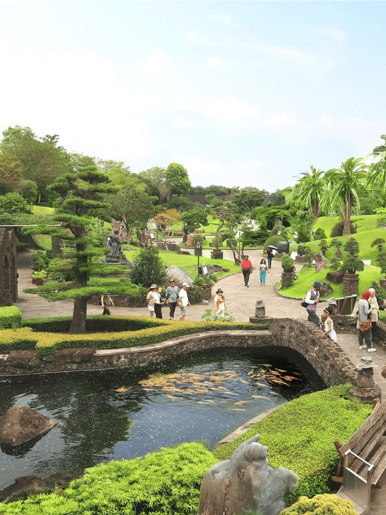 Serene Japanese botanic garden with koi pond, lush greenery, and visitors enjoying peaceful scenery.