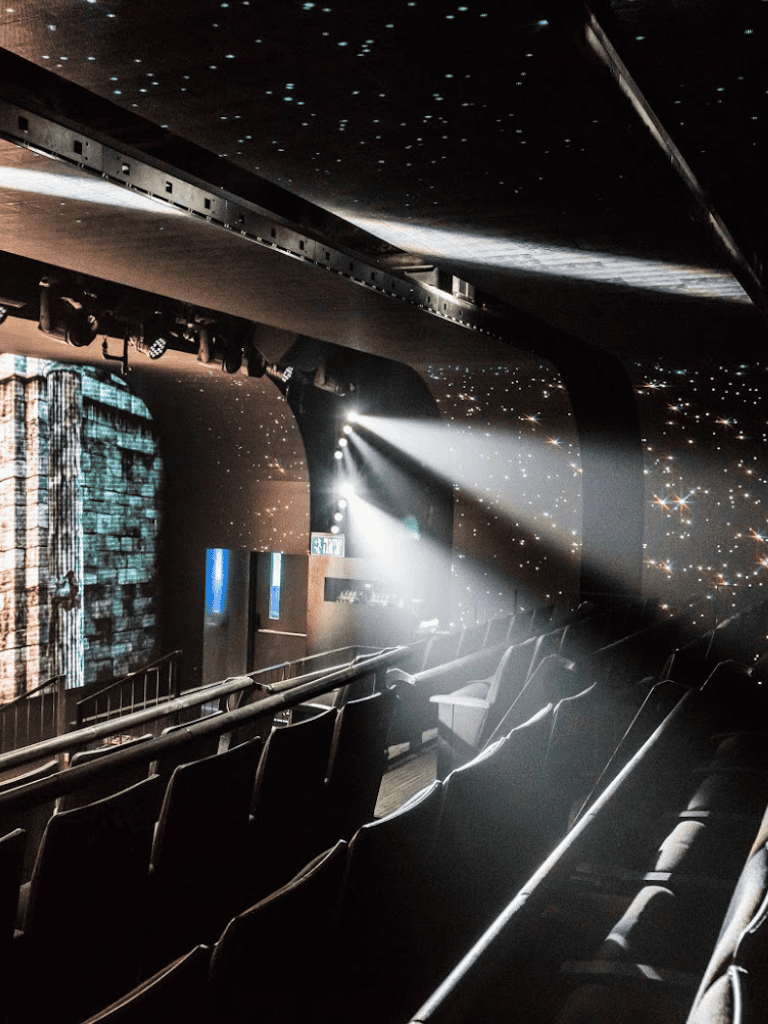 Stage theater with starry night projection and spotlight, ideal for entertainment and event hosting.